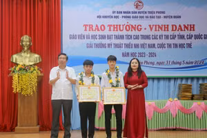 TS Lê Thị Hương, Giám đốc Sở GD&ĐT tỉnh Quảng Trị; ông Nguyễn Hữu Ngọc, Phó Bí thư Thường trực Huyện ủy Triệu Phong tặng Bằng khen của UBND tỉnh cho 2 học sinh.