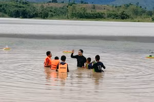 Lớp dạy bơi được tổ chức tại một hồ nước, có căng dây và phao xung quanh.