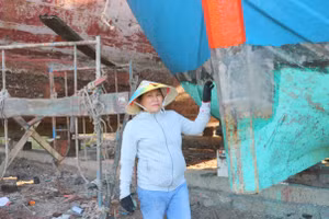 Chị Hoàng Thị Sửu vừa sửa tàu cho khách vừa kể chuyện nghề.