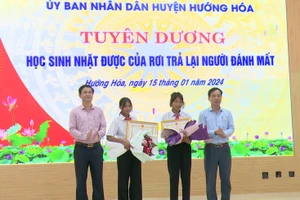 Ông Trần Bình Thuận, Chủ tịch UBND huyện (bên trái) và ông Phạm Trọng Hổ, Phó Chủ tịch UBND huyện đã biểu dương và tặng giấy khen cho hai học sinh Hồ Thị Hinh và Hồ Thị Nhỉ.