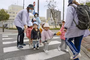 Giáo viên mầm non đi dạo với trẻ em ở thành phố Osaka.