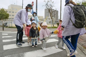 Giáo viên mầm non đi dạo với trẻ em ở thành phố Osaka.