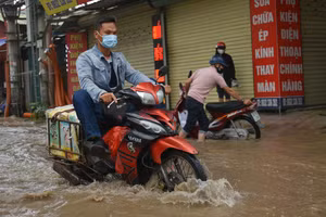 Người dân Hà Nội co chân trên xe máy lội qua đường ngập dù trời không mưa