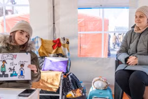 Một bé gái Ukraine 9 tuổi cầm bức vẽ về gia đình khi ngồi trong lớp học tập ở Romania.