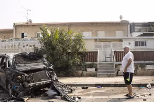 Một người đứng gần chiếc ô tô bị đốt cháy sau trận chiến giữa quân đội Israel và phiến quân Hamas ngày 8/10 tại Sderot, Israel. (Ảnh: Amir Levy / Getty Images).