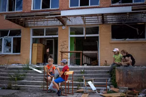 Trẻ em Ukraine vui chơi bên ngoài một tòa nhà bị phá hủy. Ảnh: INT