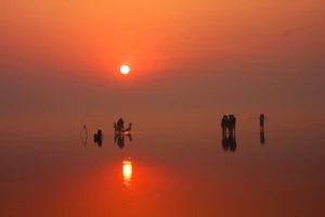 Thời điểm Mặt trời vừa ló dạng, thủy triều xuống, mặt nước cùng cát pha lẫn phù sa xâm xấp mắt cá chân tạo thành một mặt phẳng tựa như tấm gương khổng lồ phản chiếu ánh bình minh, biến khung cảnh nơi này trở nên vô cùng ảo diệu.