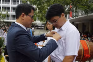 Hiệu trưởng Trường THPT Phan Châu Trinh (Đà Nẵng) gắn bảng tên cho đại diện HS lớp 10 vào trường năm học 2019 - 2020. 