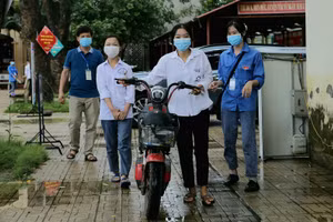 Hình ảnh thí sinh Đồng Thị Luyến dắt xe sau khi đèo bạn Ngô Thị Lan Dung (bị khuyết tật) đến Điểm thi.