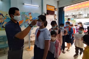 Học sinh tại Quận 5, TPHCM trở lại trường phải đeo khẩu trang và đo thân nhiệt để phòng chống dịch Covid-19 trong năm học 2020 – 2021. Ảnh: TG