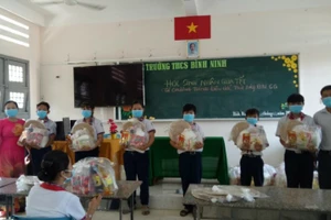 Cô Trang (trái) trao quà cho các em HS trong chương trình “Chia Tết”.