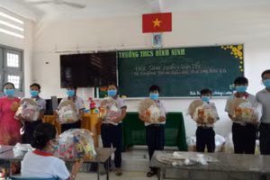 Cô Trang (trái) trao quà cho các em HS trong chương trình “Chia Tết”.