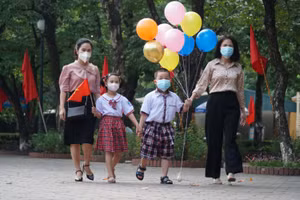 Bé Nguyễn Hạ Vi (Trường TH Hưng Dũng 2, TP Vinh) và Nguyễn Thái Sơn (Trường TH Nghi Phú 2) đại diện cho học sinh khối tiểu học Nghệ An, được mẹ đưa đến dự Lễ khai giảng năm học 2021 - 2022. Ảnh: Hồ Lài