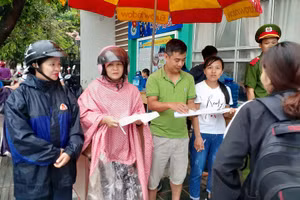 Các cô giáo Trường THPT Thanh Nưa đội mưa điểm danh “sĩ tử” trước cổng trường thi.