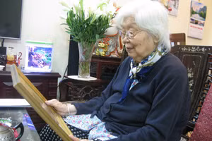 Bà Hoàng Lan Dung xem bức ảnh trong lần Bác Hồ thăm Trường Mẫu giáo Mầm non A năm 1958. 