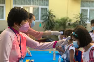 Học sinh trường tiểu học kiểm tra thân nhiệt trước khi vào trường. Ảnh: P.NGA 