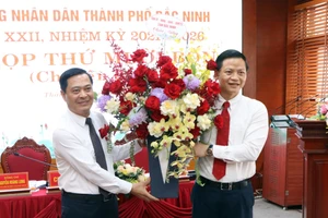 Ông Vương Quốc Tuấn - Phó Chủ tịch Thường trực UBND tỉnh Bắc Ninh (bên phải) tặng hoa chúc mừng tân Chủ tịch UBND TP Bắc Ninh Nguyễn Mạnh Hiếu.