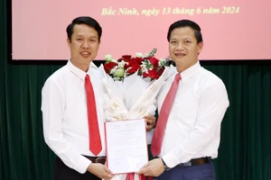 Phó Chủ tịch Thường trực UBND tỉnh Bắc Ninh- Vương Quốc Tuấn (bên phải) trao Quyết định và tặng hoa chúc mừng đồng chí Vũ Quang Khuê.