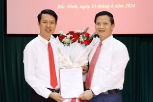 Phó Chủ tịch Thường trực UBND tỉnh Bắc Ninh- Vương Quốc Tuấn (bên phải) trao Quyết định và tặng hoa chúc mừng đồng chí Vũ Quang Khuê.