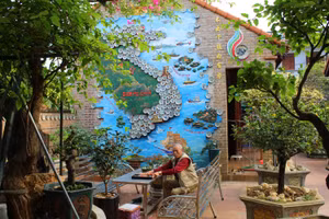 Ông Lê Xuân Năm bên bức tranh bản đồ Việt Nam được ghép từ hàng trăm chiếc đĩa. Ảnh: LT.