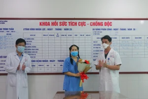 Bác sĩ Lê Đức Nhân (bìa phải) - Giám đốc bệnh viện Đà Nẵng và bác sĩ Nguyễn Thành Trung (bìa trái - PGĐ Bệnh viện tặng hoa cho nữ điều dưỡng. 