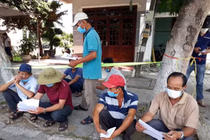 Ông Song (ngoài cùng bên phải) cùng những người khác đang ngồi chờ tại chốt kiểm soát dịch trước khi vào Đà Nẵng. 