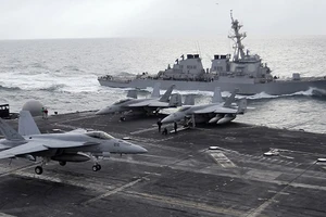 Chiến đấu cơ F-18 trên mẫu hạm Abraham Lincoln bên cạnh một tàu khu trục 