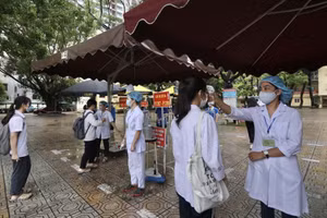 Lực lượng y tế tiến hành đo thân nhiệt cho thí sinh trước khi vào phòng thi