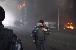 Quân nhân Ukraine đi qua một tòa nhà bị bắn phá ở Kiev.