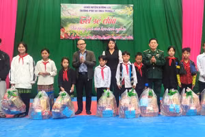 Nhà báo Hà Đồng - Phóng viên thường trú Báo Tuổi trẻ TP Hồ Chí Minh tại Thanh Hóa (người đeo kính) tặng quà học sinh nghèo tại Trường PTDTBT-THCS Trung Lý. Ảnh: TL