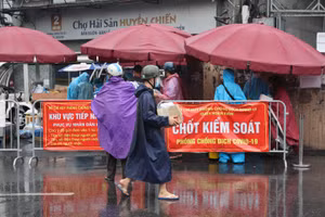 Người dân đội mưa xếp hàng đợi gửi nhu yếu phẩm vào cho người nhà trong khu cách ly.
