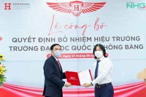 Ông Hoàng Quốc Việt - Chủ tịch Tập đoàn Nguyễn Hoàng trao quyết định, tặng hoa chức mừng cho Hiệu trưởng GS.TS Phạm Văn Lình (bên phải)