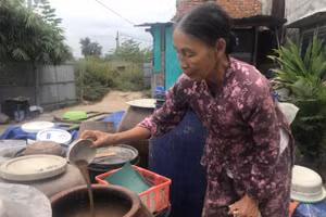 Bà Lự bên lu nước mắm đang làm. 