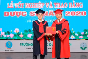 Thủ khoa Ngô Minh Khoa (bên trái) đón nhận bằng tốt nghiệp xuất sắc.