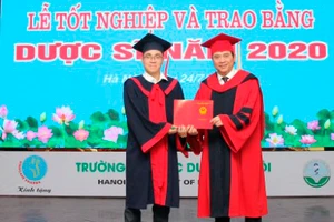 Thủ khoa Ngô Minh Khoa (bên trái) đón nhận bằng tốt nghiệp xuất sắc.