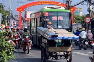 Một xe ba gác thô sơ đang vận chuyển hàng trên đường phố TPHCM.