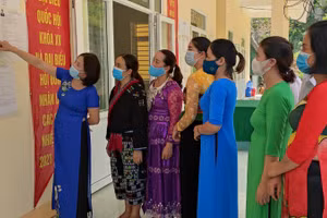 Bà Ngô Thị Lan - Hiệu trưởng Trường Tiểu học Pù Nhi, huyện Mường Lát, tỉnh Thanh Hóa (áo dài màu xanh đậm) đang cùng giáo viên nhà trường tìm hiểu danh sách các ứng cử viên tại điểm bầu cử.