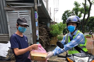 Thầy Lê Thanh Long (Trường Tiểu học Phạm Văn Hai, huyện Bình Chánh, TPHCM) giao SGK cho phụ huynh trên địa bàn huyện Bình Chánh, TPHCM.