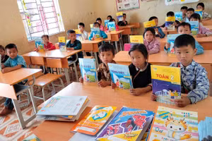 Học sinh Trường PTDTBT Tiểu học xã Ngọc Long (Yên Minh, Hà Giang) cầm trên tay những cuốn sách giáo khoa do các trường học tại Hà Nội trao tặng. Ảnh: NTCC