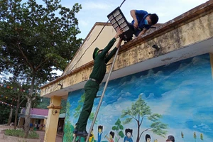 Giáo viên Trường Tiểu học Mỹ Lý 2 và bộ đội Biên phòng lắp đèn năng lượng mặt trời ở khuôn viên sân trường. 