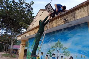 Giáo viên Trường Tiểu học Mỹ Lý 2 và bộ đội Biên phòng lắp đèn năng lượng mặt trời ở khuôn viên sân trường. 