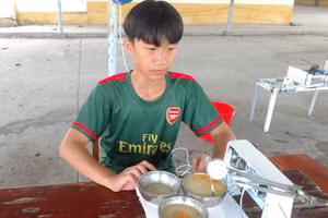 Trương Hoàng Phúc, học sinh lớp 8 Trường THCS Nguyễn Khuyến bên sáng chế robot giúp chọn món, múc và đút thức ăn.