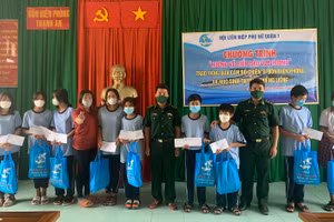 Cán bộ Đồn Biên phòng Thạnh An phối hợp với nhà hảo tâm tặng quà học sinh nghèo. 