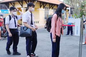 Học sinh đo thân nhiệt và khử khuẩn tay trước khi vào lớp tại Trường THPT Nguyễn Thị Minh Khai, TPHCM.