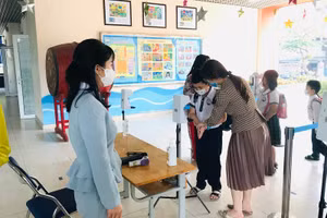 Cô Khang cùng giáo viên Trường Tiểu học Thanh Xuân Bắc đo thân nhiệt cho học sinh khi học sinh quay lại trường học trực tiếp.