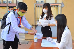 Nhân viên y tế học đường hướng dẫn học sinh Trường THCS Ninh Thành (Ninh Bình) sát khuẩn tay trước khi vào trường.