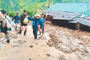 Sau cơn lũ, các thầy cô Trường Tiểu học Nhi Sơn và bà con tìm cách vào nhà lấy giấy tờ cho giáo viên 