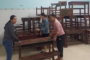 Các cô giáo Trường Tiểu học Lâm Quang Thự đang kê cao bàn ghế do nước lũ đang dâng cao. (Ảnh: Văn Hoàng)