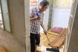 Ông Tuấn đang dọn dẹp bùn non sau 2 trận lụt. (Ảnh: Hoàng Vinh)