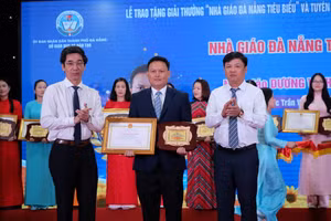 Ông Lương Nguyễn Minh Triết (áo trắng bên phải) - Phó Bí thư Thường trực Thành ủy, Chủ tịch HĐND TP Đà Nẵng và ông Trần Chí Cường (áo trắng bên trái) - Phó Chủ tịch UBND TP Đà Nẵng trao giải thưởng Nhà giáo Đà Nẵng tiêu biểu cho các giáo viên. (Ảnh: Hoàng Vinh)